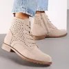 A close-up shot of a pair of beige, perforated ankle boots worn by a person. Voir les images du produit