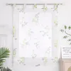 A sheer curtain with a floral pattern hangs on a curtain rod. Produktbild-Vorschau