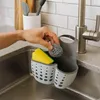 A hand is placing a steel wool scrubber into a sink organizer next to a yellow sponge. Podgląd zdjęcia produktu