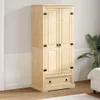 A wooden wardrobe with two doors and a drawer is shown in a room with a plant and a bed in the background. Podgląd zdjęcia produktu