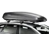 A dark gray roof box is mounted on the roof of a car. Produktbild-Vorschau