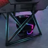 A close-up view of the base of a gaming desk with a chair underneath, featuring colorful LED lighting. Produktbild-Vorschau