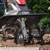 Close-up of a tiller's tines digging into the soil. Produktbild-Vorschau