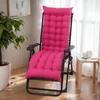 A pink cushion on a recliner chair in a room with a plant and a window. Náhled obrázku produktu