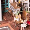 A miniature cafe scene with a counter, stools, and a small table with chairs. Anteprima dell’immagine prodotto