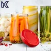 A red lid is placed in front of jars of pickled vegetables, including carrots, cauliflower, and green beans. Podgląd zdjęcia produktu
