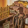A close-up view of a miniature wooden diorama, possibly a book nook, featuring stacked decorative boxes and intricate wooden railings. Náhled obrázku produktu