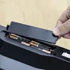 A hand is shown closing the battery compartment of a black electronic device, revealing several AA batteries inside. Podgląd zdjęcia produktu