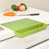 Limettenfarbenes Schneidebrett mit integrierter Seitenablage, auf einer weißen Küchenarbeitsplatte mit Gemüse und einem Messer Anteprima dell’immagine prodotto