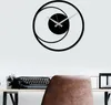 A modern black metal wall clock with a circular design is mounted on a white wall above a desk with a vintage typewriter. Anteprima dell’immagine prodotto
