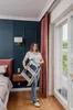 A woman is holding a folded aluminum step stool in a bedroom. Produktbild-Vorschau