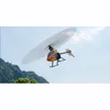 A remote-controlled helicopter flying in the sky with mountains and trees in the background. Produktbild-Vorschau