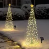 Two illuminated spiral Christmas trees with yellow stars on top, standing in the snow at night, with solar panels in front of them. Voir les images du produit