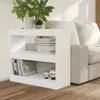 A white bookshelf is placed next to a sofa, with books and decorative items on its shelves. Náhled obrázku produktu