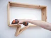 A hand is using a cordless drill to attach a wooden shelf to a white wall. Podgląd zdjęcia produktu