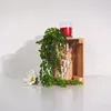 A wooden crate with a plant, a candle, and a flower. Produktbild-Vorschau