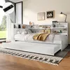 A white daybed with a pull-out trundle bed, set up in a bedroom with a window and decorative items on the shelves. Produktbild-Vorschau