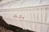 A close-up view of a bed base with the word "Fluffy" embroidered on it. Produktbild-Vorschau