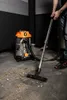 A person is using a wet/dry vacuum cleaner to clean up debris on a concrete floor. Podgląd zdjęcia produktu