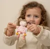 A young girl is holding a small doll. Náhľad obrázku produktu