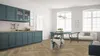 A modern kitchen and dining area with blue cabinets and furniture, a white sofa, and large windows. Produktbild-Vorschau