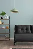 A living room scene with a dark gray sofa, a shelf unit with decor, and a light green pendant lamp. Náhled obrázku produktu