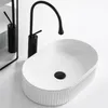 A white oval countertop sink with a black faucet. Podgląd zdjęcia produktu