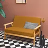 A mustard yellow loveseat with wooden legs is placed on a black and white checkered floor, next to a large potted plant and decorative vases. Anteprima dell’immagine prodotto
