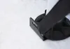 A close-up of a black strap attached to a black plastic base, resting on a white textured surface. Anteprima dell’immagine prodotto