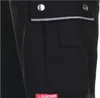 A close-up view of a black work pant pocket with a reflective stripe and a logo. Produktbild-Vorschau