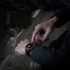 Schwarze robuste Smartwatch am Handgelenk einer Person, mit Anzeige von Anrufoptionen, die mit einem Finger angetippt wird Náhled obrázku produktu