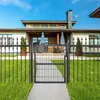A modern house with a black metal fence and gate in the foreground, set against a clear blue sky. Produktbild-Vorschau