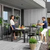 A man and a woman are on a patio with a dining set. The man is holding a chair, and the woman is standing by the table. Náhled obrázku produktu