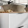 A close-up view of a bathroom vanity with a stone sink and a ribbed white cabinet. Produktbild-Vorschau