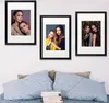 Three framed pictures of women hanging on a wall above a bed with pillows and books. Produktbild-Vorschau