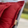 A close-up of a red cushion on a chair, with a brand tag visible. Produktbild-Vorschau