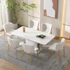 A dining set with a white table and six beige chairs with gold legs, set in a modern dining room. Produktbild-Vorschau
