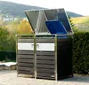 A modern trash bin enclosure with two compartments, set in a garden or outdoor patio area with a scenic background of rolling hills and houses. Produktbild-Vorschau