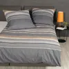 A neatly made bed with striped bedding and pillows. Produktbild-Vorschau