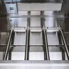 Close-up view of the interior of a stainless steel gas grill, showing the burners and heat deflector. Podgląd zdjęcia produktu