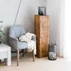 A living room scene with a chair, a wooden pedestal, and decorative items. Voir les images du produit