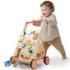 A baby is pushing a wooden walker with various interactive toys on it. Produktbild-Vorschau