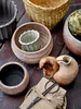 A collection of terracotta pots and a basket on a wooden surface. Produktbild-Vorschau
