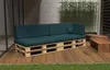 An outdoor patio setting with a sectional sofa made of pallets and dark green cushions, accompanied by wooden coffee tables and bamboo plants. Produktbild-Vorschau