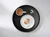 A festive holiday scene with a mug of coffee, cookies, and a small gift on a black tray. Produktbild-Vorschau
