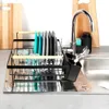 A dish drying rack filled with clean dishes and cutlery placed on a kitchen counter next to a sink and faucet. Náhled obrázku produktu