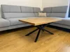 A wooden coffee table with a black metal base is placed in front of a gray sectional sofa. Anteprima dell’immagine prodotto