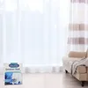 A box of Dr. Beckmann Gardinen Weiß detergent is placed on a wooden floor in front of sheer white curtains. A beige armchair with a blanket is visible to the right. Podgląd zdjęcia produktu