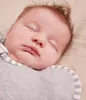 A close-up of a sleeping baby wearing a swaddle. Produktbild-Vorschau