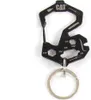 A black multi-tool keychain with various tools and measurements etched onto it, attached to a silver keychain ring, set against a white background. Produktbild-Vorschau